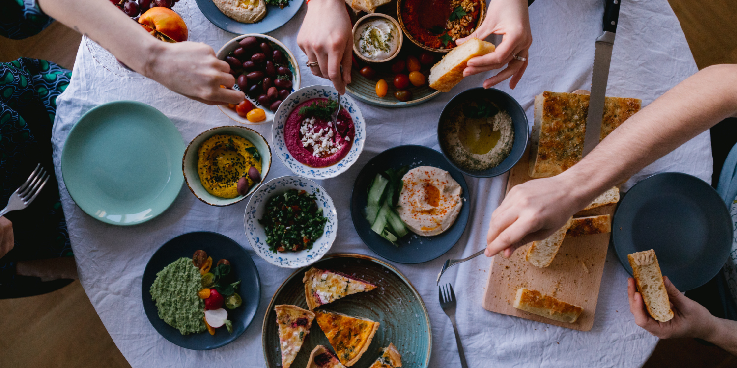 Mesa com vários pratos de comida partilhados por um grupo de pessoas