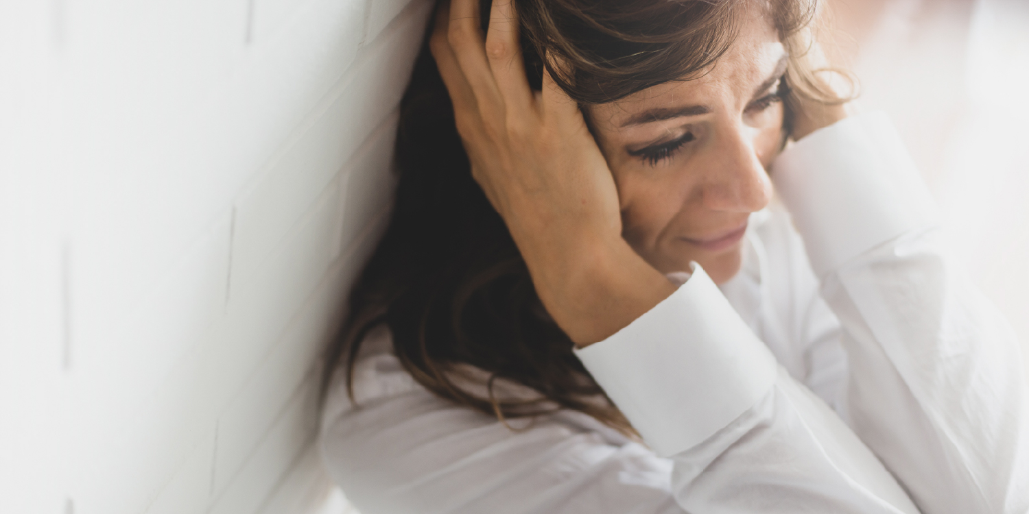 Mulher pensativa com as mãos na cabeça durante uma crise existencial