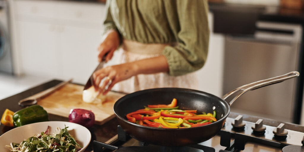 Pessoa a cozinhar legumes salteados numa frigideira